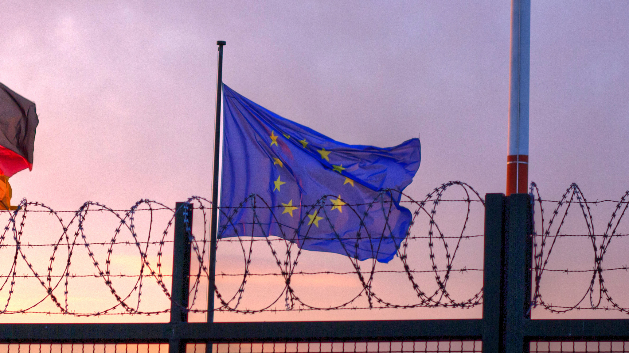 The flag of the European Union flying in from of barbed wire