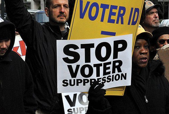 Photo showing part of a crowd of people, who are holding placards saying 'Stop Voter Suppression'