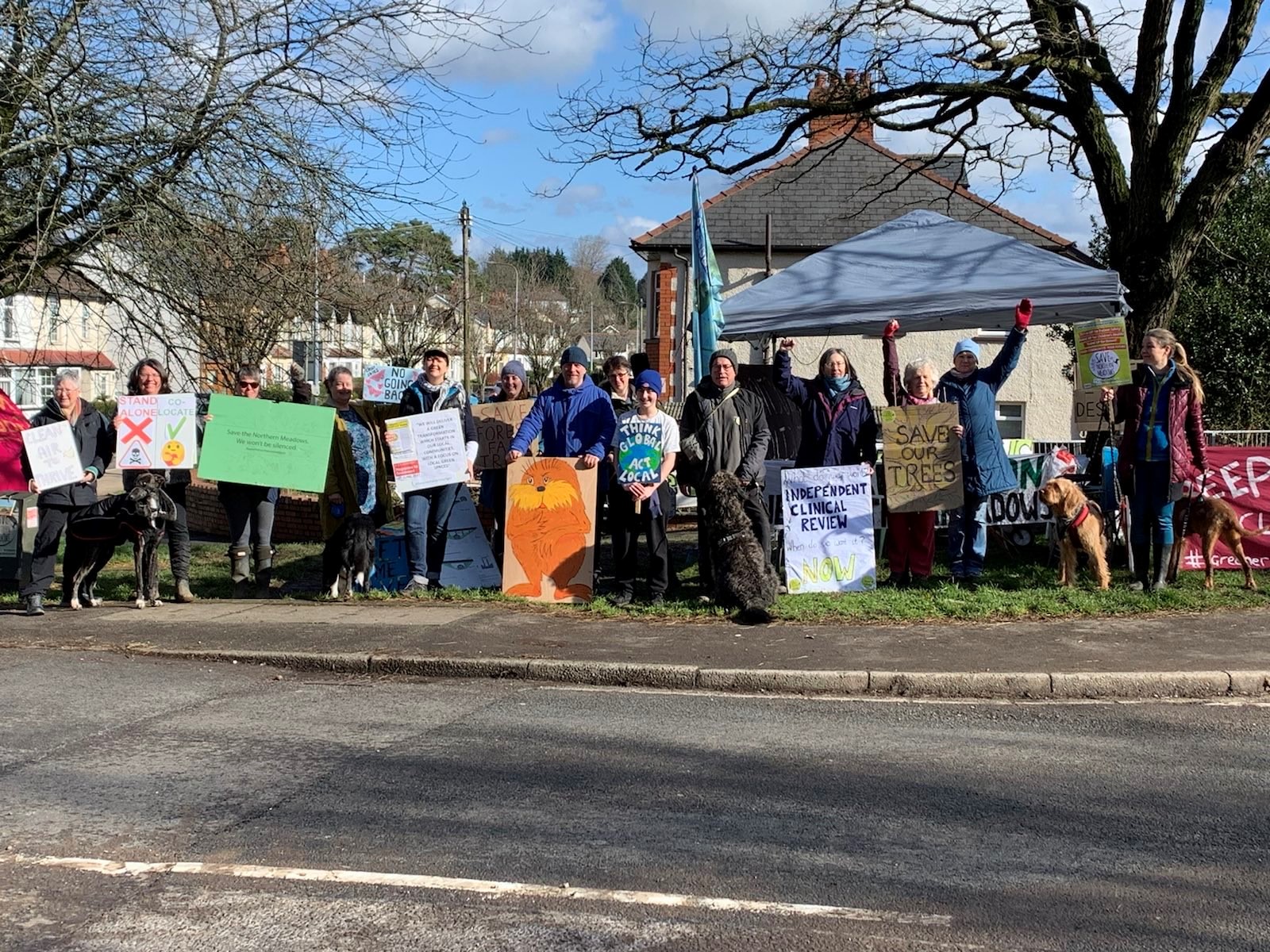 Group of people with banners relating to Save the Northern Meadows Campaign standing in front of a marquee